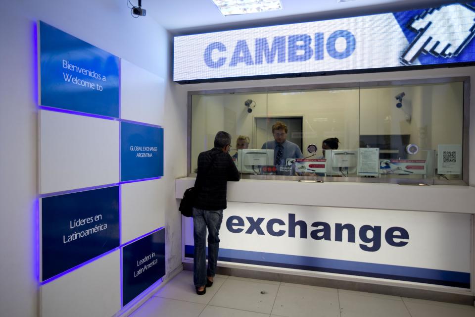 A man gets information about how to buy dollars at foreign exchange business in Buenos Aires, Argentina, Monday, Jan. 27, 2014. The Argentine government announced Friday it was relaxing restrictions on the purchase of U.S. dollars. The measure would start taking effect Monday, allowing Argentines to buy dollars for personal savings, reversing a 2012 restriction. (AP Photo/Natacha Pisarenko)