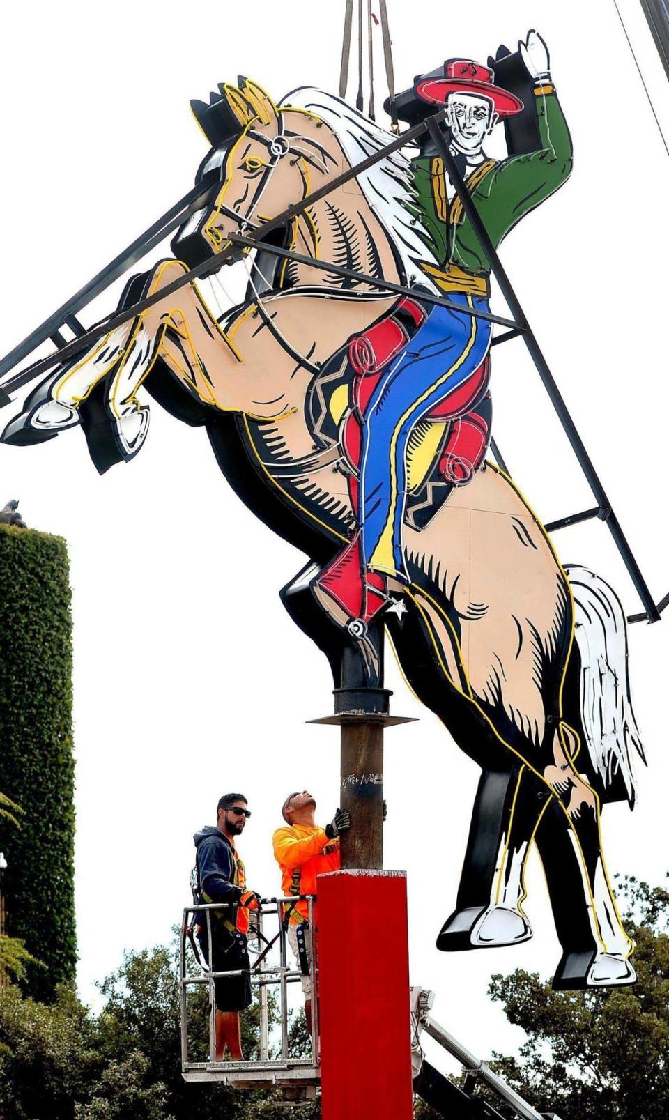 The historic neon sign of the waving vaquero from the old Hacienda resort, astride his rearing steed rides again as brothers Lamar, left, and Leroy Hall, right, of A Plus Signs, get set to remove the protective steel frame, after the sign was mounted in its position overlooking the Big Fresno Fair’s Paul Paul Theater, Monday morning, Oct. 3, 2016. The sign was purchased by Friends of the Fair board members Mike and Debbie Kludjian and donated to the fair for its growing collection of historic local neon signs. A Plus Signs worked several weeks on restoration -- around 80 hours were spent on the neon; the same on the paint, which was brought back to its original state.