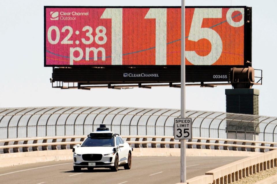 A Waymo self-driving car on Seventh Street as the temperature of 115 degrees is displayed on a digital billboard in downtown Phoenix, Arizona on Monday (via REUTERS)