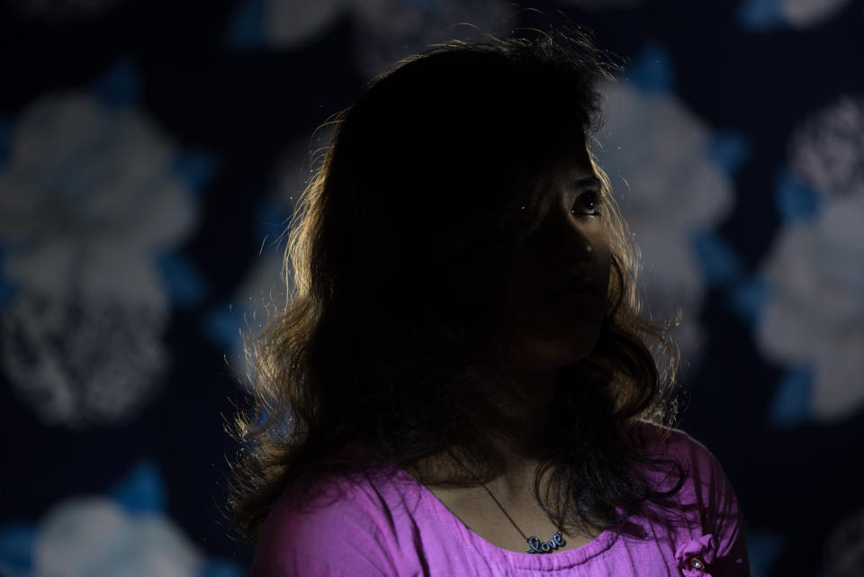 A girl with wavy hair in a purple bodice, her face in shadow.