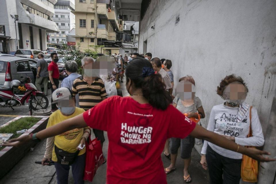 One of KSK's volunteers asking their patrons to form a line before their food distribution in Pudu, KL. — Picture by Hari Anggara.

