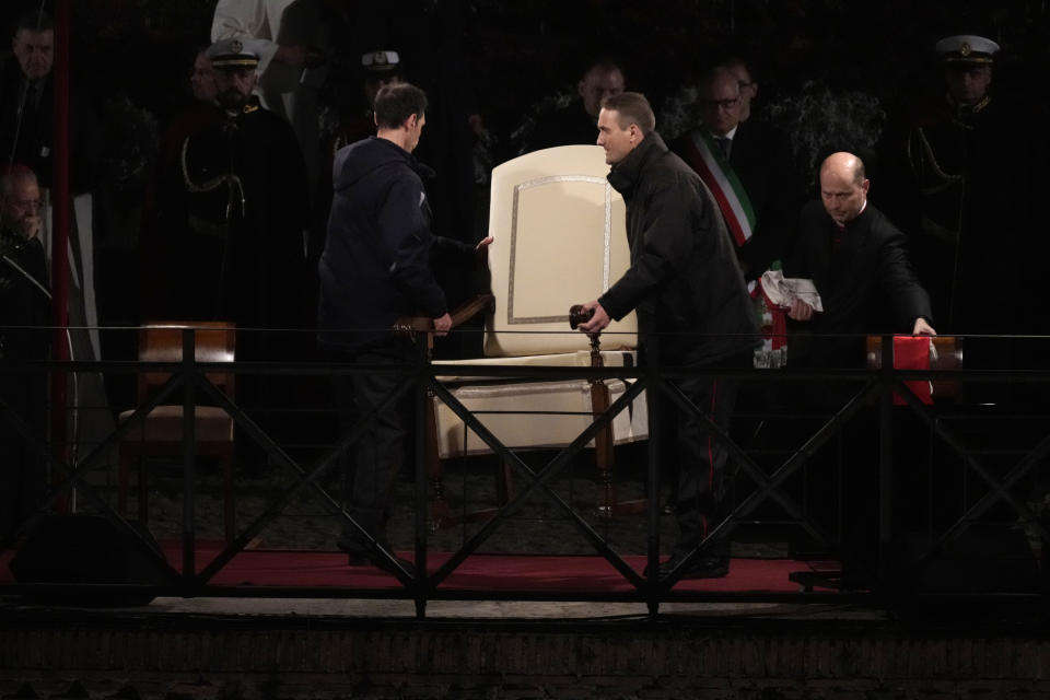 Vatican ushers carry away the Pope Francis' chair prior to the start of the Via Crucis (Way of the Cross) at the Colosseum on Good Friday, in Rome, Friday, March 29, 2024. (AP Photo/Gregorio Borgia)