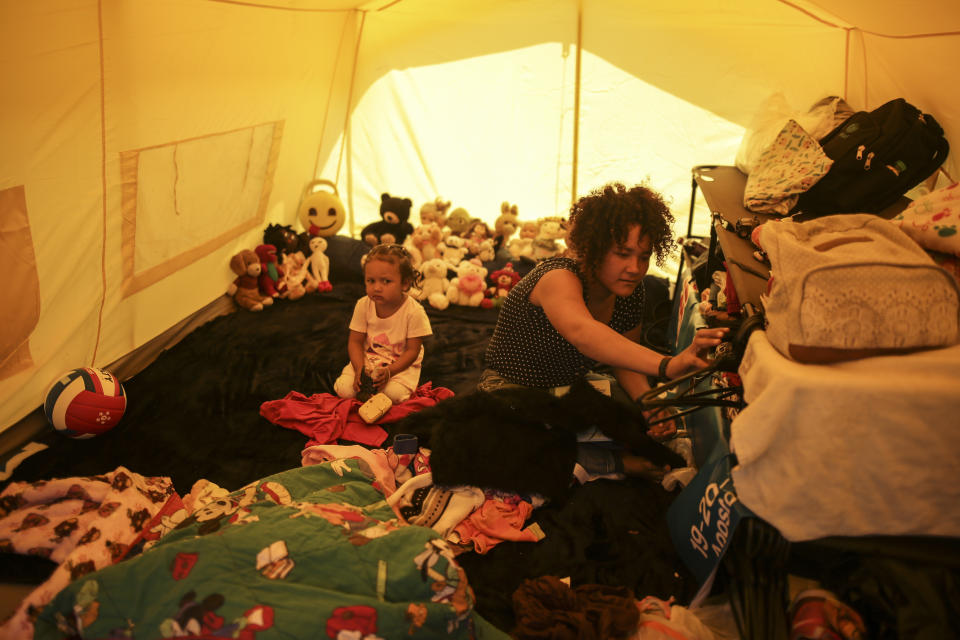 Samir Gonzalez sits with her daughter inside their tent in a camp for homeless Venezuelan migrants, in Bogota, Colombia, Wednesday, Nov. 21, 2018. The camp was built by the city's social welfare secretary to accommodate migrants who had previously been living in tents made of plastic sheets and scrap materials outside the city's bus terminal. (AP Photo/Ivan Valencia)