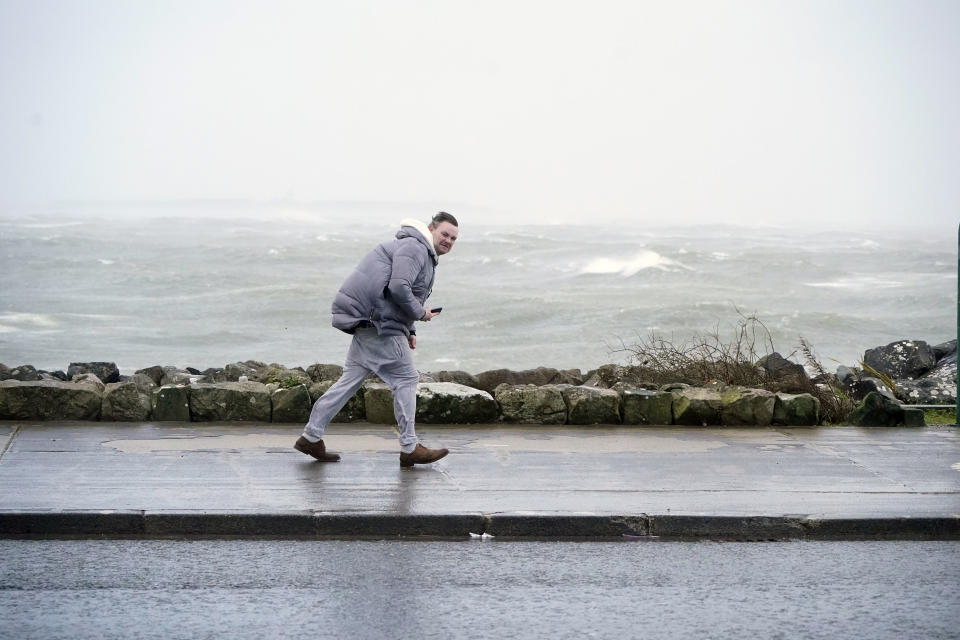 A man walking in high winds at Salthill, Ireland, Sunday, Jan. 21, 2024, during Storm Isha. A Status Red wind warning has been issued for counties Donegal, Galway and Mayo as authorities warn people to take care ahead of Storm Isha's arrival. (Niall Carson/PA via AP)