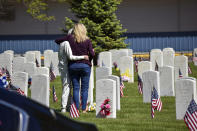 Two women embrace next to a grave at the veterans' cemetery at Mountview Cemetery in Billings, Mont., Monday, May 25, 2020. No new cases of the coronavirus were reported in Montana on Monday for the fifth straight day. (AP Photo/Matthew Brown)