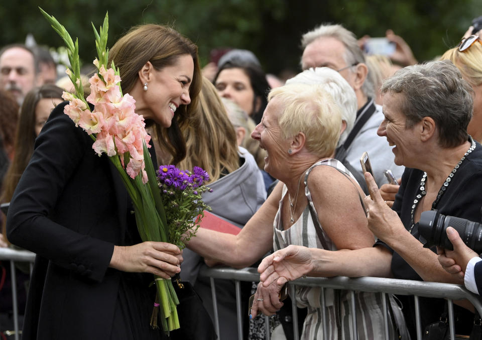 Kate, Princess of Wales reacts with a well-wisher as she and Prince William, view floral tributes left by members of the public, in memory of late Queen Elizabeth II, at the Sandringham Estate, in Norfolk, England, Thursday, Sept. 15, 2022. Queen Elizabeth II, Britain's longest-reigning monarch died Thursday Sept. 8, 2022, after 70 years on the throne. (Toby Melville/Pool via AP)