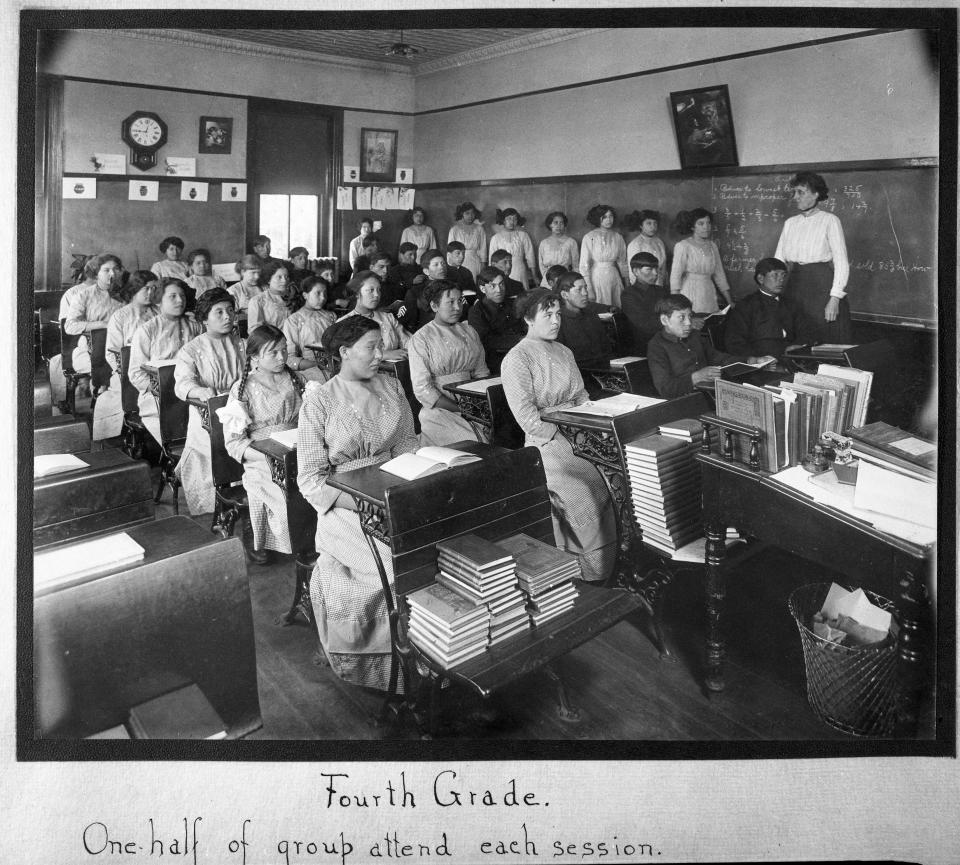In this undated photo provided by National Archives, fourth grade students sit in a classroom at the former Genoa Indian Industrial School in Genoa, Nebraska. Researchers are now trying to locate the bodies of more than 80 Native American children buried near the school in central Nebraska. For decades, the location of the student cemetery has been a mystery, lost over time after the school closed in 1931 and memories faded of the once-busy campus that sprawled over 640 acres in the tiny community of Genoa. (National Archives via AP)