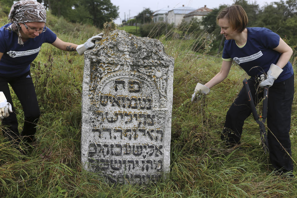 In this photo taken on Aug. 29, 2018, volunteers clean an old Jewish cemetery in Rohatyn, the site of a Jewish Heritage project, close to Lviv, Ukraine, a few days before the 75th anniversary of the annihilation of the city's Jewish population by Nazi Germany. The Ukrainian city of Lviv, once a major center of Jewish life in Eastern Europe, is commemorating the 75th anniversary of the annihilation of the city's Jewish population by Nazi Germany and honoring those working today to preserve that vanished world. The commemoration comes amid a larger attempt in Ukraine to preserve the memories of the prewar Jewish community.(AP Photo/Yevheniy Kravs)