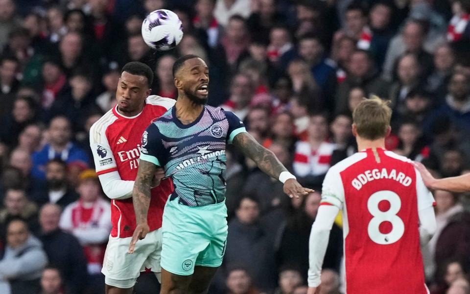 Arsenal's Gabriel, left, and Brentford's Ivan Toney, centre, challenge for the ball during the English Premier League