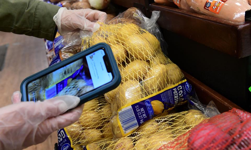 Instacart employee Monica Ortega uses her cellphone to scan items for an order