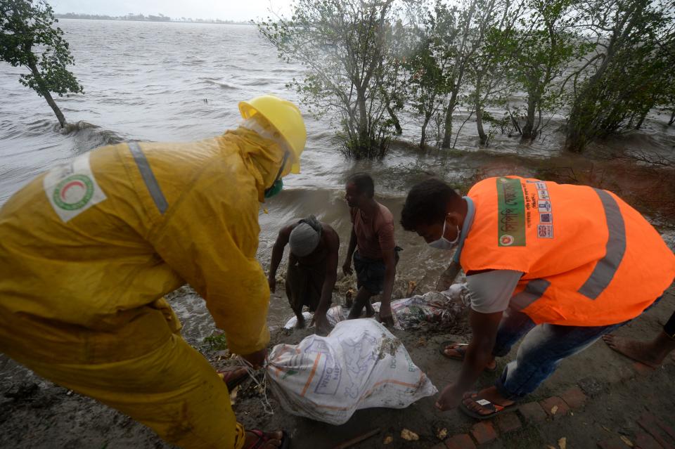 Workers and villagers reinforce an embankment with sacks of soil ahead of the expected landfall of cyclone Amphan, in Dacope on May 20, 2020. - Several million people were taking shelter and praying for the best on Wednesday as the Bay of Bengal's fiercest cyclone in decades roared towards Bangladesh and eastern India, with forecasts of a potentially devastating and deadly storm surge. Authorities have scrambled to evacuate low lying areas in the path of Amphan, which is only the second "super cyclone" to form in the northeastern Indian Ocean since records began. (Photo by Munir Uz zaman / AFP) (Photo by MUNIR UZ ZAMAN/AFP via Getty Images)