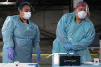 Nurses check on the status of rapid COVID-19 tests at a drive-through testing site in a parking garage in West Nyack, N.Y., Monday, Nov. 30, 2020. The site was only open to students and staff of Rockland County schools in an effort to test enough people to keep the schools open for in-person learning. (AP Photo/Seth Wenig)