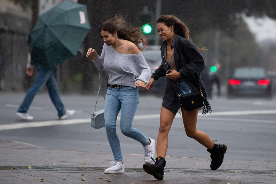 Two girls hold hands and run through Manly in Sydney as strong winds blow their hair. Source: AAP/file picture