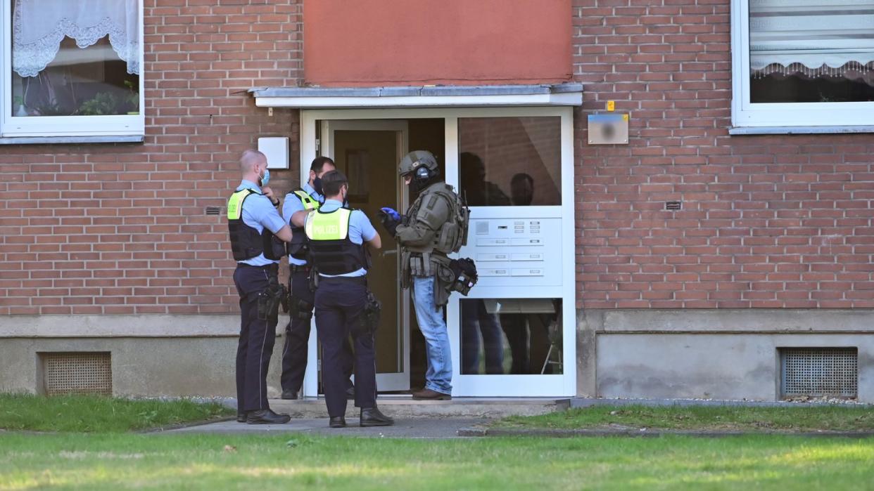 Polizei und ein SEK-Beamter stehen vor der Eingangstür eines Mehrfamilienhauses in krefeld. In einer Wohnung im Haus hat sich möglicherweise ein Mann mit vier Kindern verschanzt.