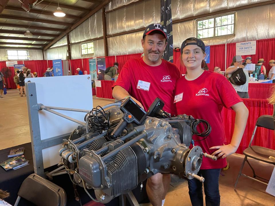David Clemens and his daughter, Mary, stand in front of an airplane engine, one of the exhibition booths at KidVenture at EAA AirVenture on July 25, 2022.
