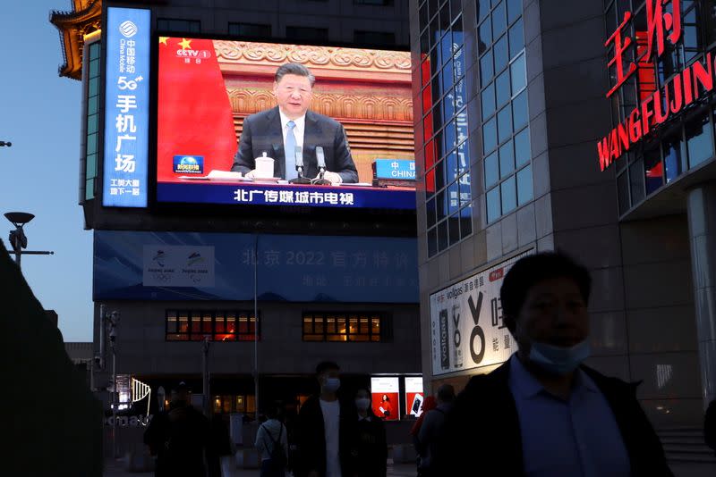 FILE PHOTO: Giant screen shows news footage of Chinese President Xi Jinping attending a video summit on climate change, in Beijing