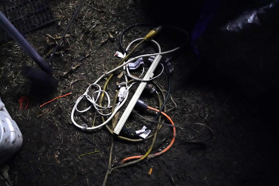 A jumble of electrical cords lies on the wet ground outside the tent Cristin and Ricky Trahan are now living in, in Lake Charles, La., Thursday, Dec. 17, 2020. They were hit by Hurricanes Laura and Delta. She, Ricky and a son are living in tents on the property of their destroyed home, while her other son, his fiancée and their one-year old son are living in a loaned camper there. A relative's home on the same property is now gutted and they are living in a camper as well. (AP Photo/Gerald Herbert)