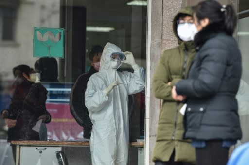 A nurse, wearing protective clothing, looks at a thermometer at a hospital in Wuhan -- epicentre of the China virus outbreak