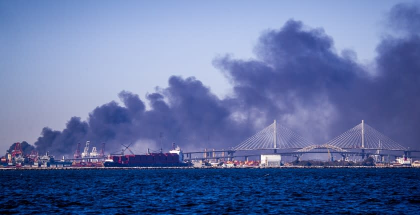 Long Beach, CA - October 13 A large fire at a commercial yard in the Long Beach/Carson area sends thick black smoke into the air as viewed off the coast of Long Beach Wednesday, Oct. 13, 2021 in Long Beach, CA. (Allen J. Schaben / Los Angeles Times)