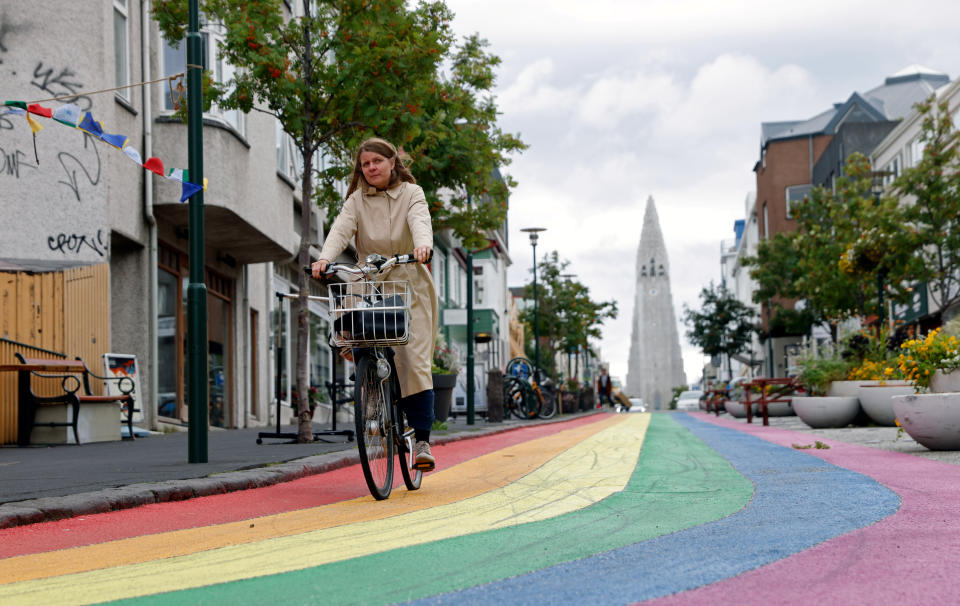 A woman cycles down a street painted in rainbow colours near the Hallgrimskirkja church, in Reykjavik, Iceland. The world's largest trial of a four-day working week in Iceland proved a success. Photo: John Sibley/Reuters