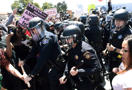 Police in riot gear hold back demonstrators against U.S. Republican presidential candidate Donald Trump outside the Hyatt hotel where Trump is set to speak at the California GOP convention in Burlingame, California April 29, 2016. REUTERS/Noah Berger