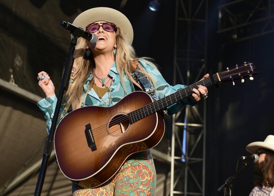 lainey wilson playing the guitar and singing into a microphone on stage