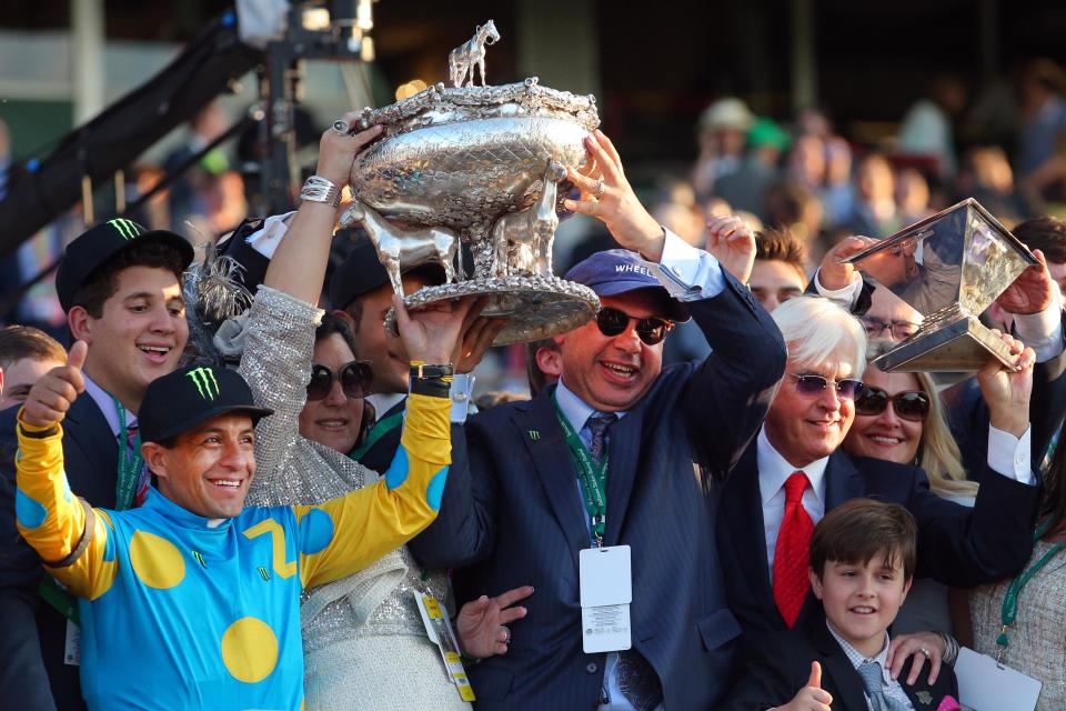 American Pharoah trainer Bob Baffert, right, hoists the Triple Crown trophy, while jockey Victor Espinoza and owner Ahmed Zayat hold the Belmont trophy after American Pharoah completed the Triple Crown sweep in 2015.