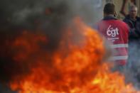 A striking French CGT labour union employee stands near a barricade to block the entrance of the depot of the SFDM company near the oil refinery to protest the the governments proposed labor law reforms in Donges, France, May 26, 2016. REUTERS/Stephane Mahe