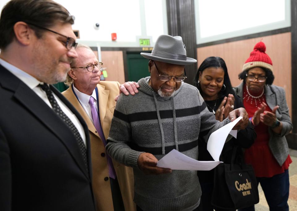 Glynn Simmons reads the court order Tuesday as his attorneys Joe Norwood and John Coyle, left, niece Cecilia Hawthorne and Madeline Jones, right, look on after Judge Amy Palumbo ruled to approve Simmons' "actual innocence" claim.