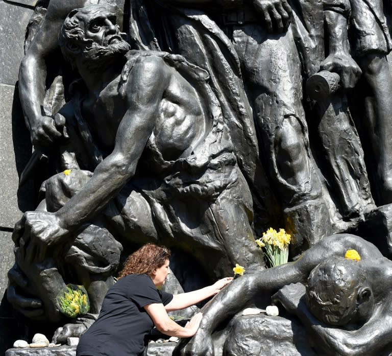 A woman lays flowers at the Ghetto Heroes Monument in Warsaw in April amid controversy over a law, amended Wednesday, which imposed jail terms on anyone saying the Polish state was responsible for the Nazi Holocaust