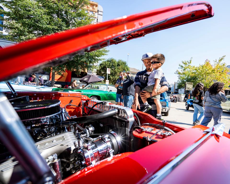 Gustavo Avalos of Milwaukee holds his 2 year-old brother, Matteo Gomez, as they look at the different cars at the 5th Annual "El Grito en Calle 5" Car Show and Festival hosted by Ranflitas Milwaukee car club on Saturday, September 23, 2023, in Milwaukee.