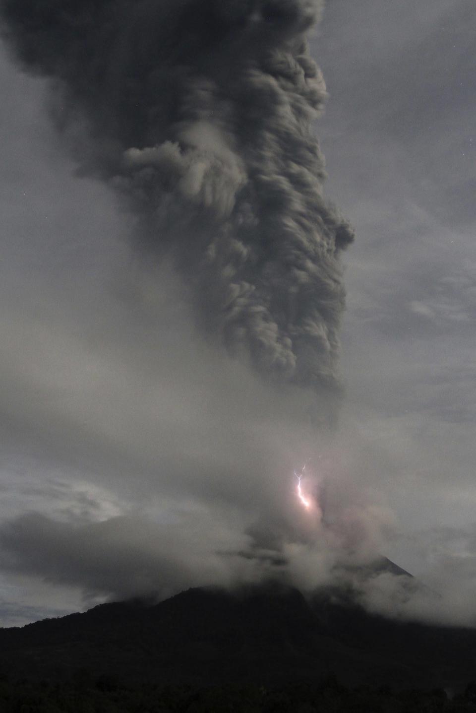 Lightning flashes as Mount Sinabung spews ash in a view from Tiga Pancur village in Karo district