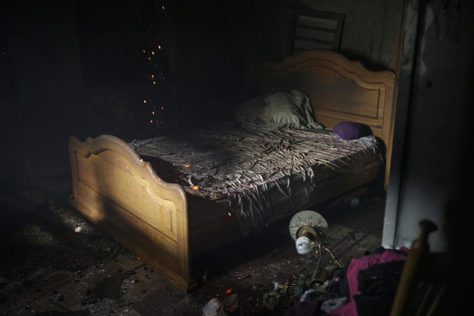 Embers smolder on a bed as firefighters work to extinguish a fire at a house after a Russian attack in Kharkiv, Ukraine, Monday, April 11, 2022. (AP Photo/Felipe Dana)