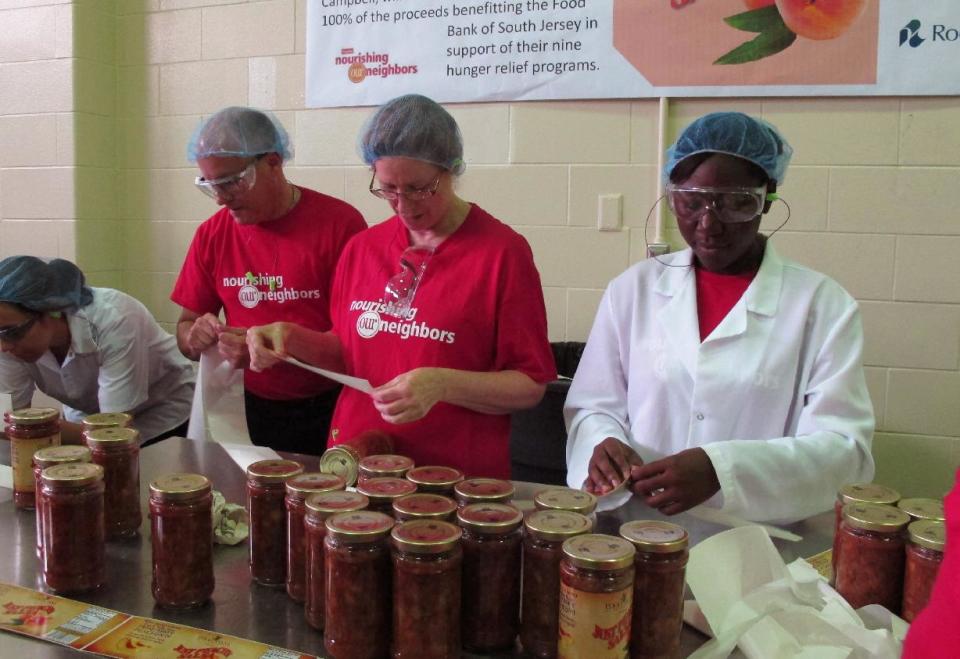 Campbell Soup Co. workers put labels on jars of Just Peachy Salsa at the Campbell headquarters in Camden, N.J., on Wednesday, Aug. 1, 2012. Campbell and other firms are donating ingredients, materials and manufacturing for the salsa, which is being sold by the Food Bank of South Jersey. (AP Photo/Geoff Mulvihill)