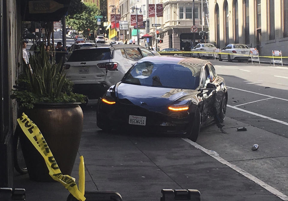 FILE - In this Sunday, July 21, 2019 file photo shows the scene after a woman was arrested after running a red light in a rented Tesla in San Francisco and causing a crash that killed a tourist and left his wife critically injured. San Francisco police said Wednesday, July 24, 2019, preliminary information shows a rented Tesla that was speeding when it ran a red light and struck a couple was not on semi-autonomous Autopilot mode. (Kate Larsen/KGO-TV via AP,File)