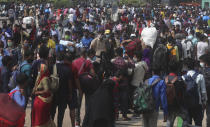 People wearing masks as a precaution against the coronavirus stand in queues to board trains at Lokmanya Tilak Terminus in Mumbai, India, Wednesday, April 14, 2021. India is experiencing its worst pandemic surge, with average daily infections exceeding 143,000 over the past week. (AP Photo/Rafiq Maqbool)