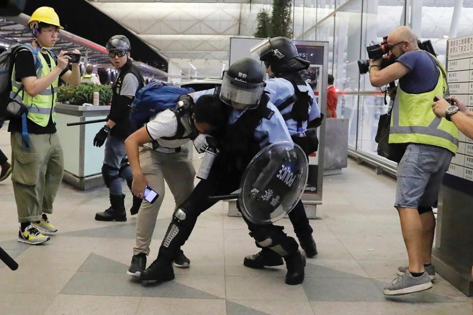 Policemen in riot gears arrest a protester during a demonstration at the Airport in Hong Kong, Tuesday, Aug. 13, 2019. (AP Photo/Kin Cheung)