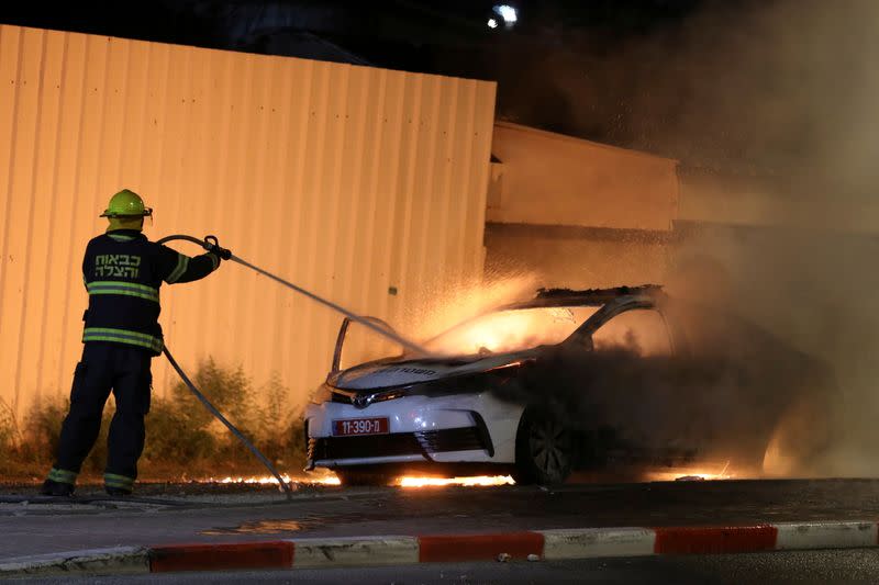 FILE PHOTO: An Israeli firefighter extinguishes a burning Israeli police car during clashes between Israeli police and members of the country's Arab minority in the Arab-Jewish town of Lod
