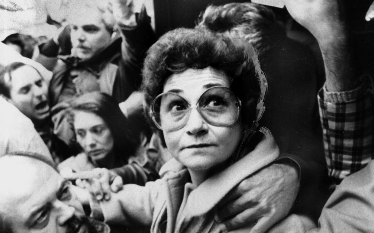 Juanita Castro is helped on to the back of a van as she prepares to speak to a cheering crowd against her brother, Fidel Castro, outside the Cuban Mission in New York, late 1970s