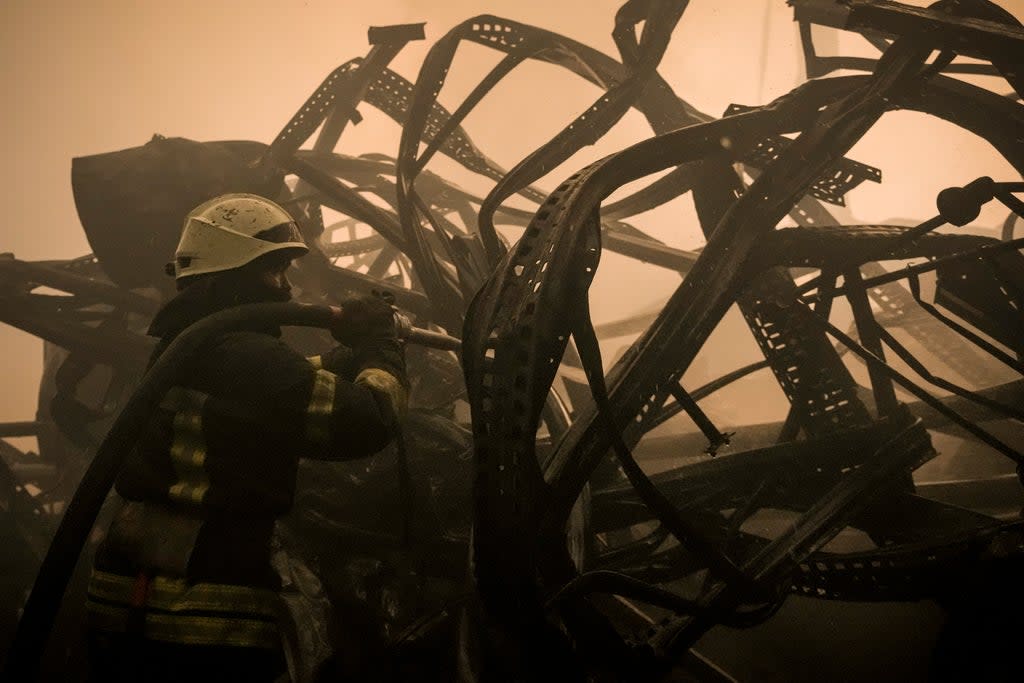 A Ukrainian firefighter extinguishes fire inside a large food products storage facility which was destroyed by an airstrike on the outskirts of Kyiv (Vadim Ghirda/AP) (AP)