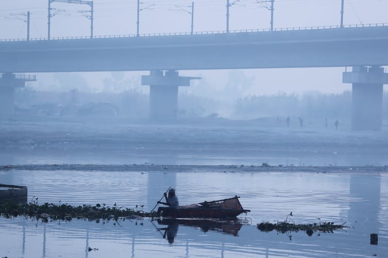 A man paddles a home-made boat across Yamuna river on a smoggy morning in New Delhi