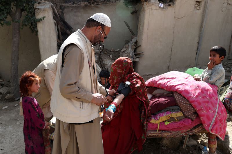 An Afghan woman is treated by a doctor in an area affected by an earthquake in Gayan