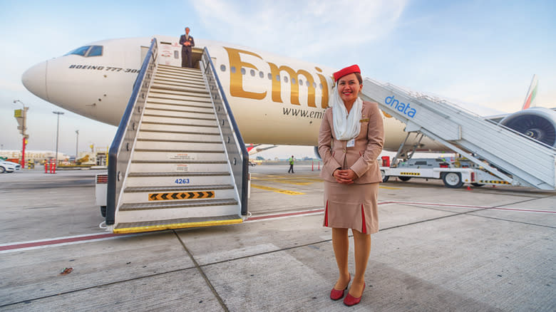 An Emirates crew member in front of plane