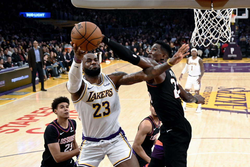 Los Angeles Lakers' LeBron James (23) goes up to basket under pressure from Phoenix Suns' Deandre Ayton (22) during the second half of an NBA basketball game Wednesday, Jan. 1, 2020, in Los Angeles. (AP Photo/Ringo H.W. Chiu)