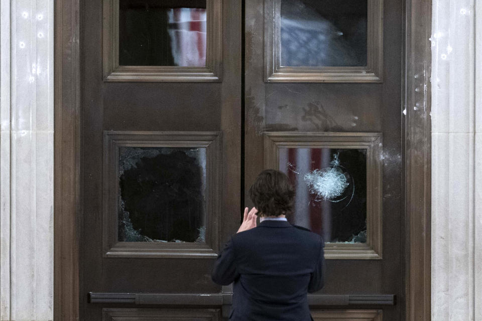 A man takes a photo of broken windows near the Rotunda in the early morning hours of Thursday, Jan. 7, 2021, after protesters stormed the Capitol in Washington, on Wednesday. (AP Photo/Andrew Harnik)