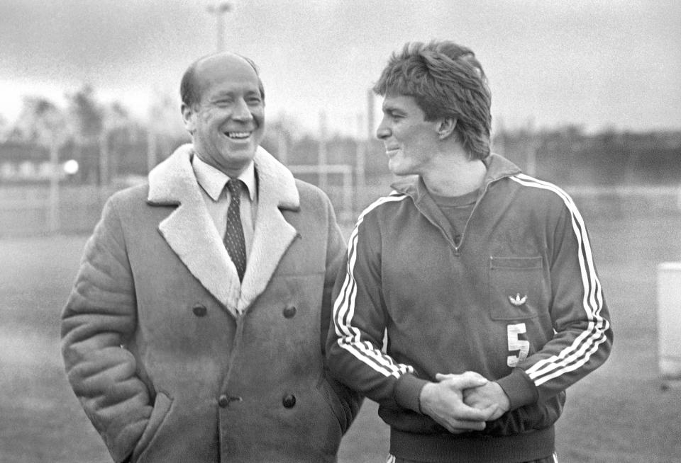 FILE - Former English soccer player Bobby Charlton, left, talks with VFB Stuttgart defender Karl-Heinz Foerster in Stuttgart, West Germany, Jan. 13, 1984. Bobby Charlton, an English soccer icon who survived a plane crash that decimated a Manchester United team destined for greatness to become the heartbeat of his country's 1966 World Cup-winning team, has died. He was 86. A statement from Charlton's family, released by United, said he died Saturday Oct. 21, 2023 surrounded by his family. (AP Photo/Thomas Meyer, file)