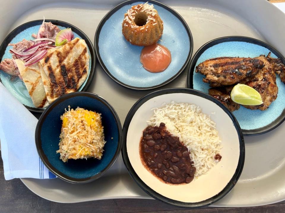Array of plates at Beach Club at Bimini on Virgin Voyages featuring chicken, beans, cake, rice, and other foods