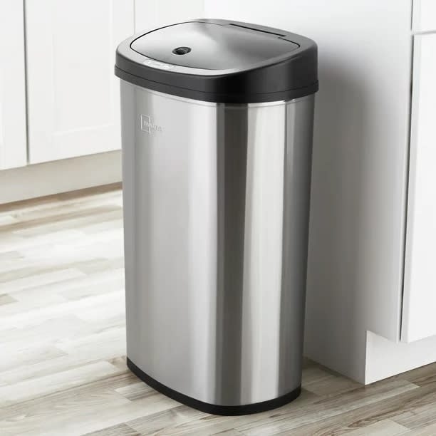 Stainless steel trash can in a kitchen with white cabinets