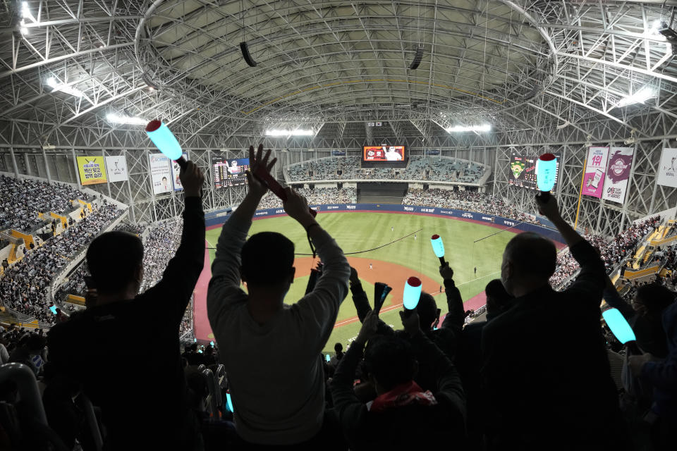 FILE - Fans wearing face masks as a precaution against the coronavirus cheer their teams during the second baseball game of the Korean Series between Doosan Bears and KT Wiz at Gocheok Skydome in Seoul, South Korea, on Nov. 15, 2021. (AP Photo/Ahn Young-joon, File)