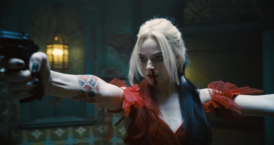 Harley Quinn stands holding up two guns